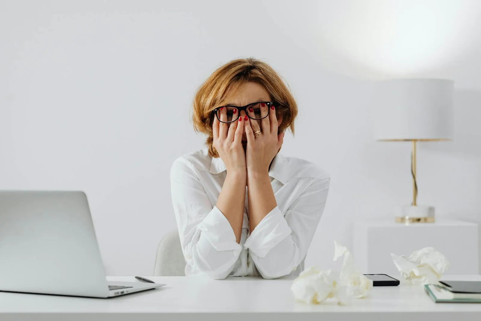 A tired woman at her desk with her hands on her face — a moment of stress-driven exhaustion