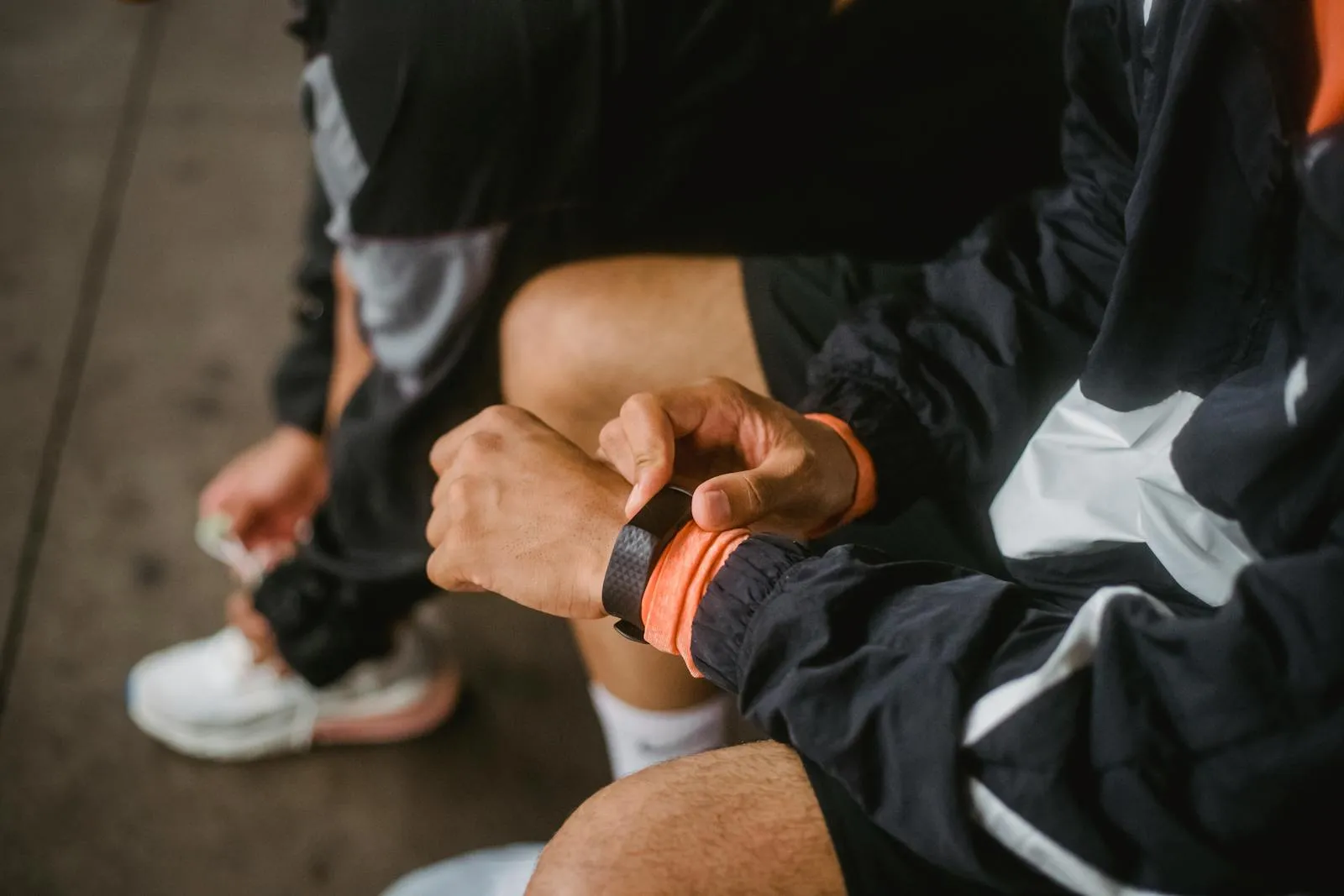 An athlete in athletic wear adjusts a smartwatch before starting a workout