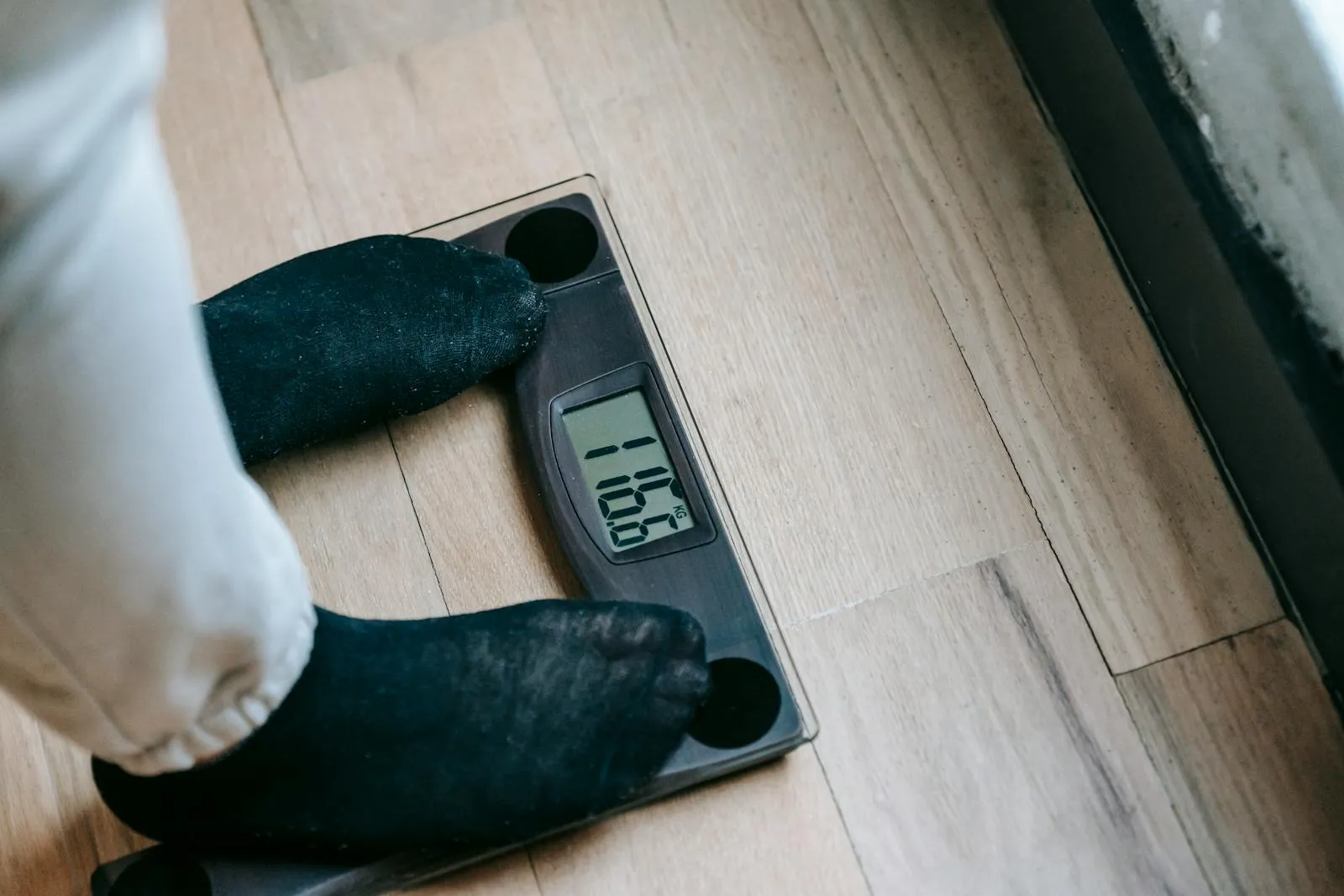 A person steps on an electronic weighing scale to check progress mid-diet
